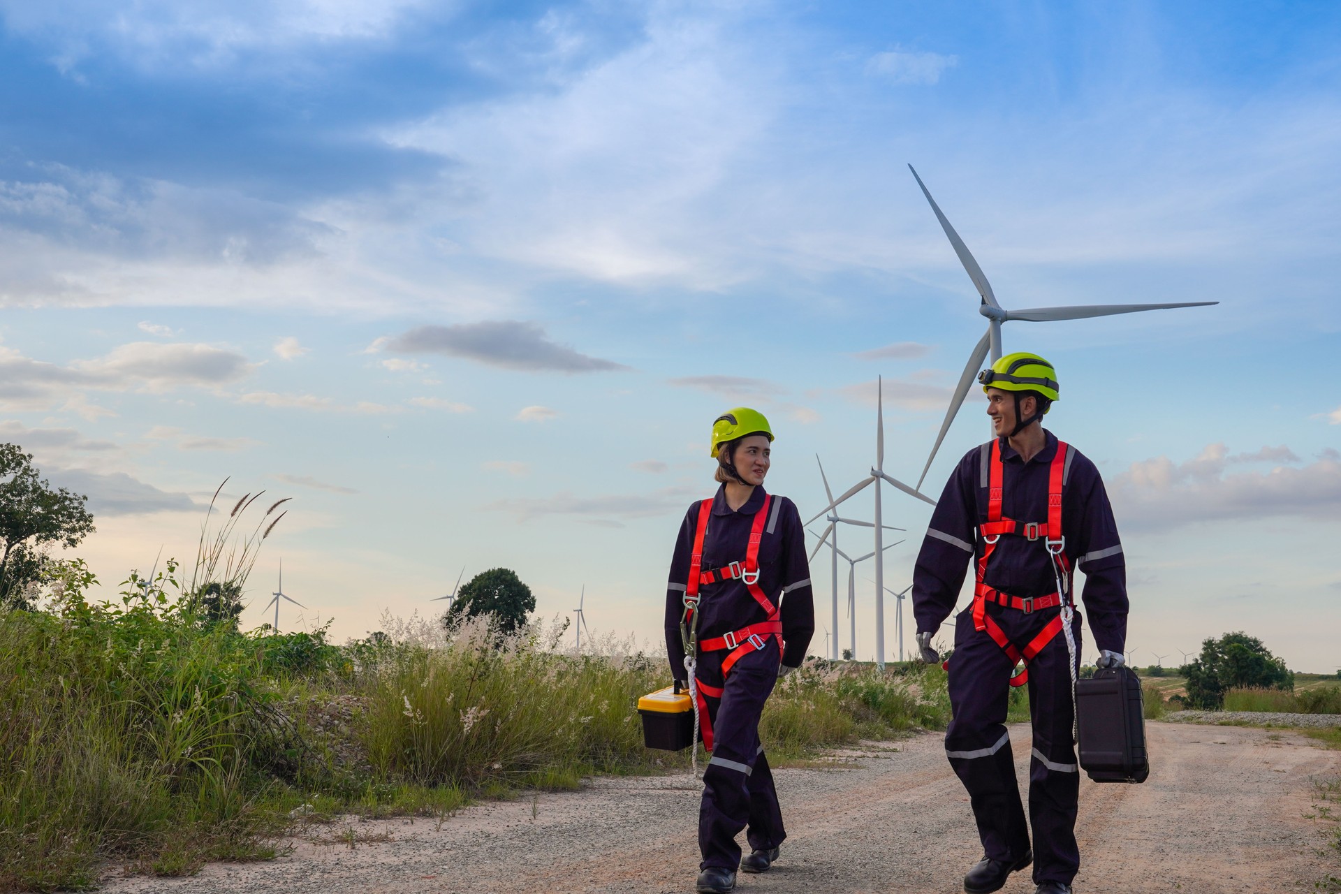 Male and female engineers maintenance wind turbine farm.